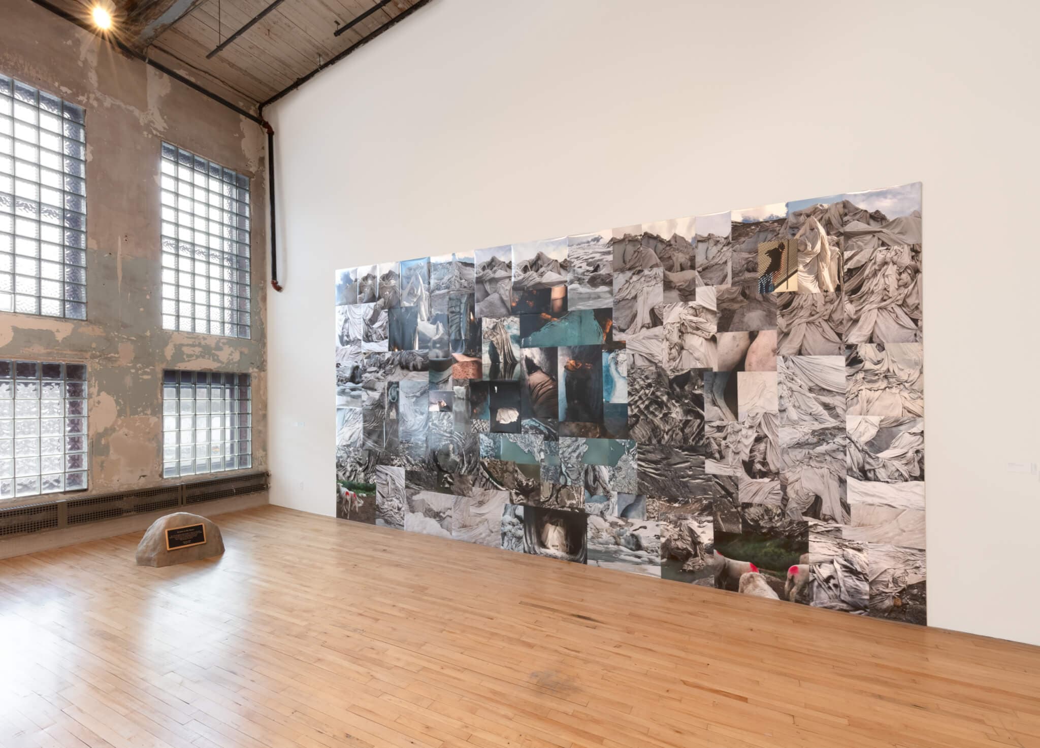 A large collaged work of glacier photographs covers a gallery wall.